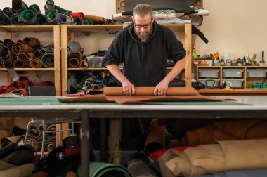 Beyaz sakallı adam bir atölyede bronzlaştırıcı olarak çalışıyor.