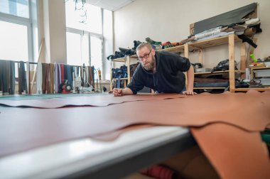 Beyaz sakallı adam bir atölyede bronzlaştırıcı olarak çalışıyor.