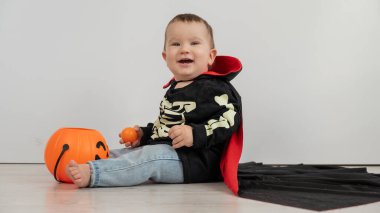 Beyaz arka planda şeker sepeti tutan Dracula Cadılar Bayramı kostümlü beyaz tatlı çocuk.