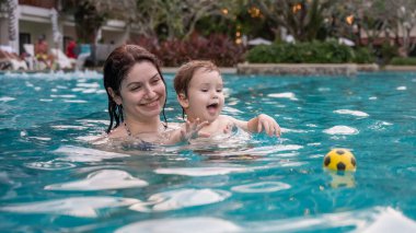 Beyaz kadın tatilde havuzda yüzerken oğlunu kucağına aldı