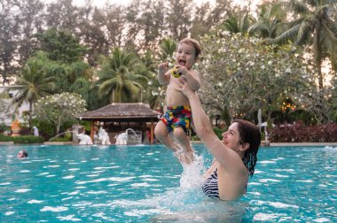 Beyaz kadın tatilde havuzda yüzerken oğlunu kucağına aldı