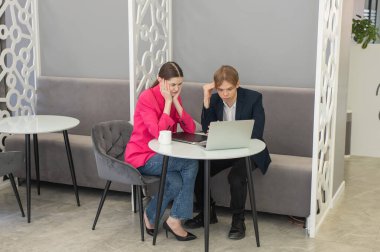 Meslektaşlar dizüstü bilgisayarda oturup iş konuşuyorlar.