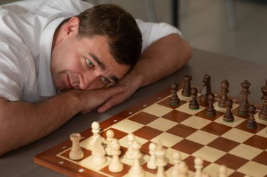 Orta yaşlı beyaz adam satranç oynuyor.