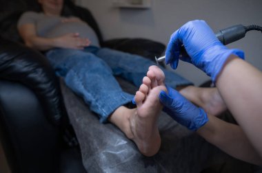 Güzellik salonunda hırdavat pedikür yapan hamile bir kadın.