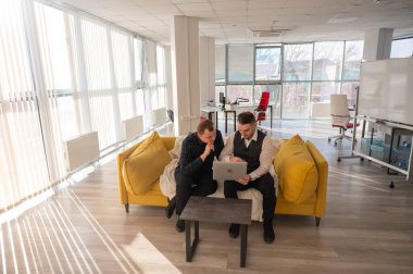 İki beyaz adam dizüstü bilgisayara bakıyor ve iş tartışıyorlar.