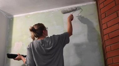 Kafkas kadın silindirle duvar boyuyor.