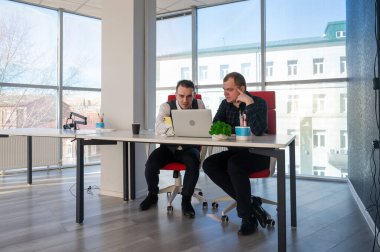 İki beyaz adam bir masada oturup iş tartışıyorlar.