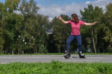 Beyaz kadın parkta paten kayıyor.