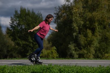 Beyaz kadın parkta paten kayıyor.