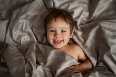 Beyaz tenli şirin bir çocuğun yatakta yatışının üst görüntüsü.