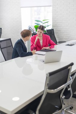 Kadın ve erkek ofiste otururken konuşuyorlar.