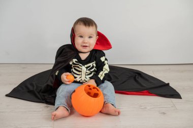 Beyaz arka planda şeker sepeti tutan Dracula Cadılar Bayramı kostümlü beyaz tatlı çocuk.