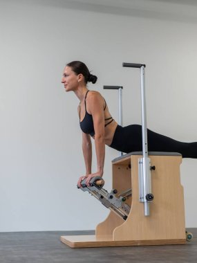 Beyaz kadın klasik sandalyede pilates yapıyor.