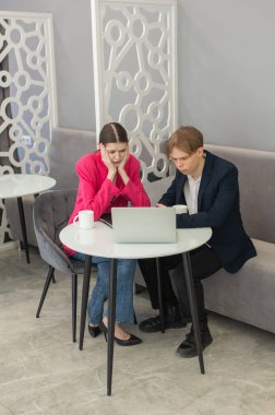 Meslektaşlar dizüstü bilgisayarda oturup iş konuşuyorlar.