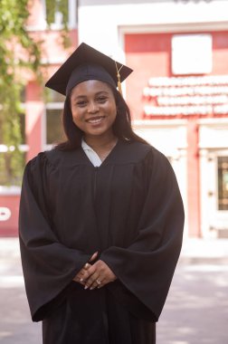 Mezuniyet elbisesi içinde mutlu bir Afrikalı kadın.