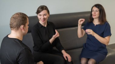 Bir adam ve iki kadın Rusça işaret diliyle konuşuyorlar.