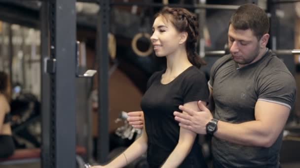 Panienka robi przedni hantle loki i instruktor mężczyzna trzyma ręce w nowoczesnej siłowni. — Wideo stockowe