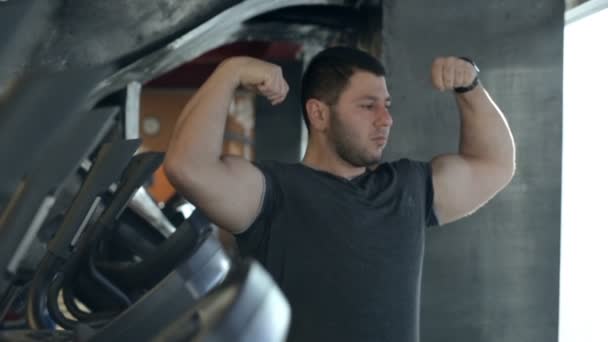 Porträtt av idrottsman, som visar hans biceps i moderna gym. — Stockvideo