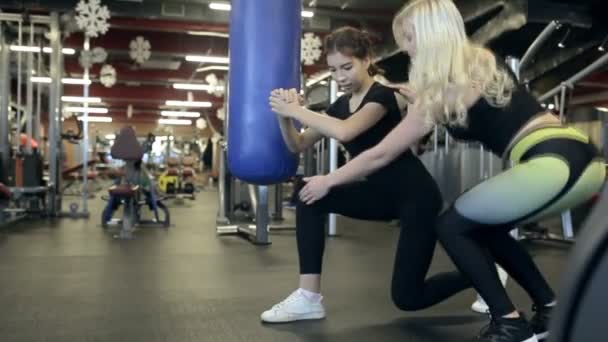 Personal entrenador femenino ayuda a la chica a tomar una pose en el gimnasio . — Vídeos de Stock