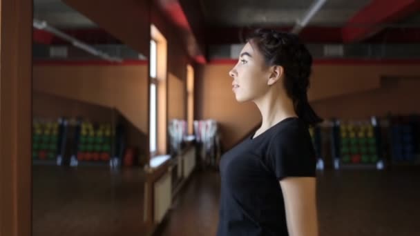 Portrait of young sportswoman, who is warming up her shoulders in modern gym. — Stock Video