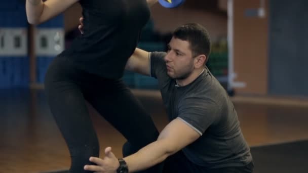 Persoonlijke trainer leert een meisje te doen een oefening met barbell op haar schouders. — Stockvideo