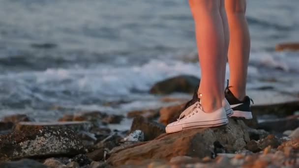 岩が多い海岸の行に立っている若い女性 2 人の足. 動画クリップ