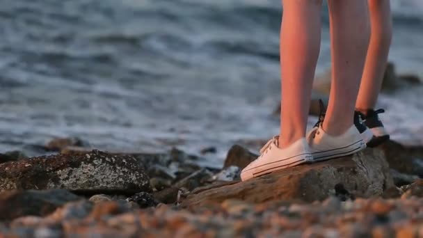 Nogi dwie kobiece turystów stoi nad brzegiem morza w godzinach wieczornych. — Wideo stockowe