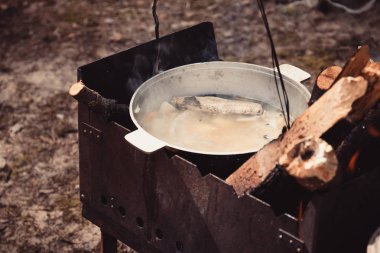 Kamp ateşi üzerinde bir tencerede pişirme kulak