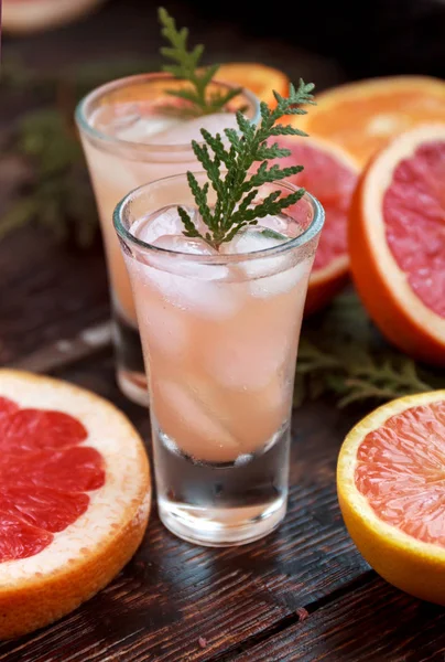 Alcoholic cocktail with grapefruit and citrus, ice and juice, drink glass on a wooden board, old rustic style, selective focus — Stock Photo, Image