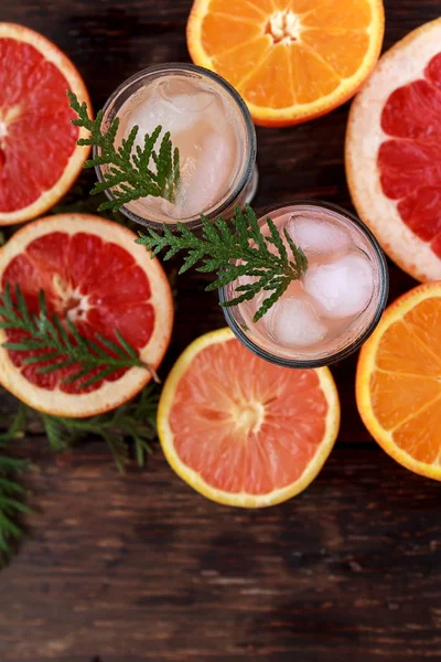 Alcoholic cocktail with grapefruit and citrus, ice and juice, drink glass on a wooden board, old rustic style. — Stock Photo, Image