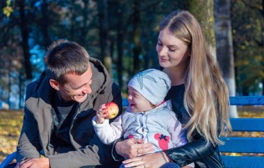 bir adam bir kadın ve bir çocuk sonbaharda bir bankta oturur
