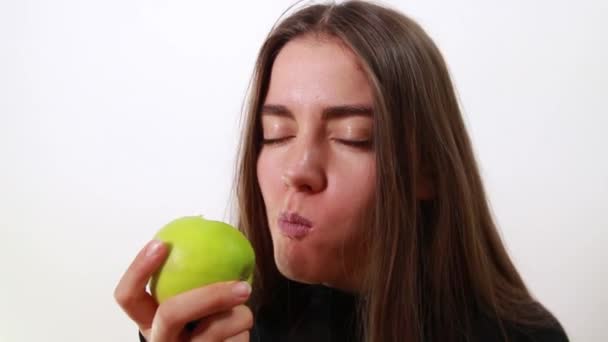 Jong mooi meisje bijt een groene appel. — Stockvideo