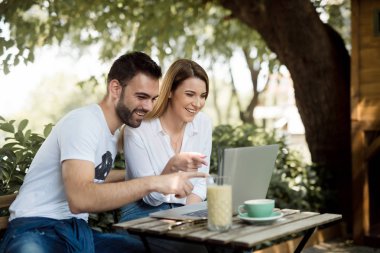 Mutlu çift kahve dükkanında laptop yanında çalışma