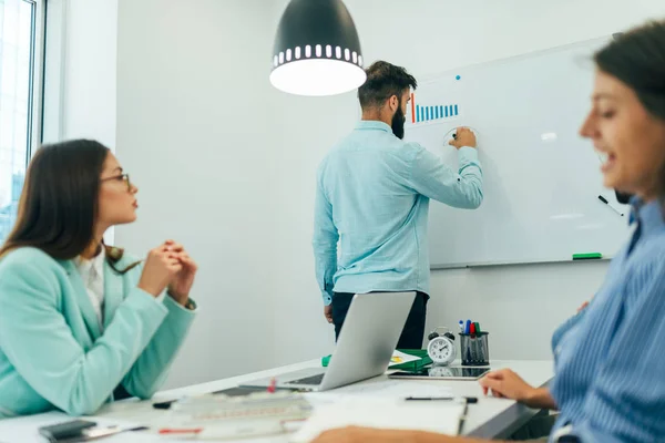 Businessman with young partners looking at whiteboard in creative office