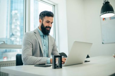 Ofisteki masasında oturan genç adamın portresi.