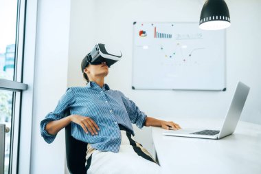 Ofiste otururken VR kulaklık giyen genç iş kadını