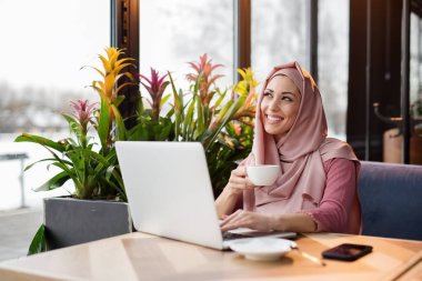 Café'de çalışma ve bilgisayarı kullanan Müslüman kadın
