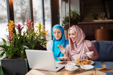 Café'de çalışma ve bilgisayarı kullanan Müslüman kadınlar