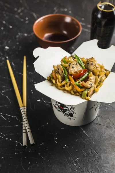 中国面条在一个盒子里 鸡肉和蔬菜用棍子 从黑暗背景的餐馆从侧视图的Wok食品交付 — 图库照片
