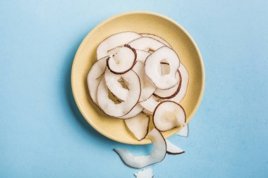 Mavi arka planda sarı bir tabakta Hindistan cevizi cipsi