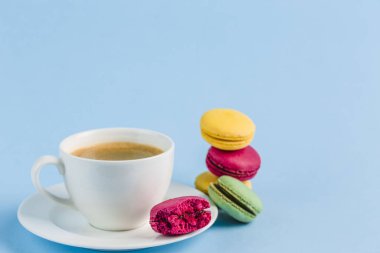 Mavi bir backgrou üzerinde kahve beyaz bir Fincan ile renkli macaroons