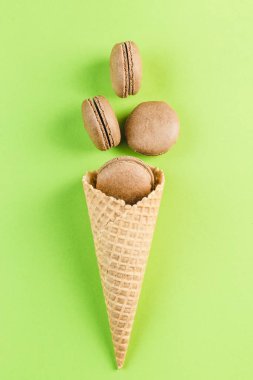 Yeşil bir arka plan üzerinde bir waffle koni çikolata macaroons, üst 