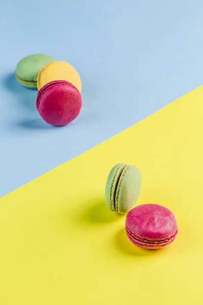 Multicolored macaroons on a blue and yellow background, top view — Stock Photo, Image