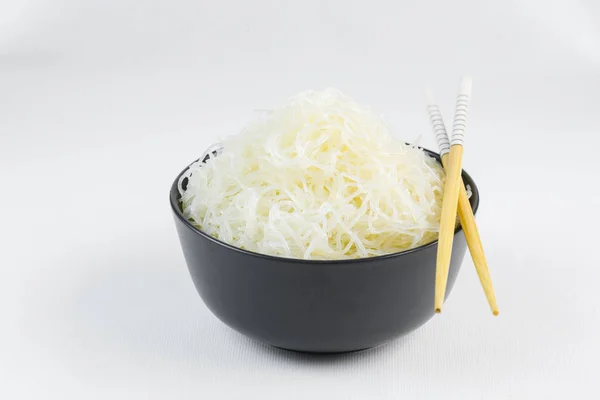 Fideos de arroz celofán en un tazón negro con palillos en blanco — Foto de Stock