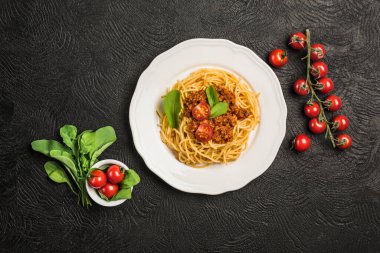 Lezzetli klasik İtalyan Bolonez makarnası domatesli ve koyu arkaplanda fesleğenli. Üst görünüm, yatay yönelim.