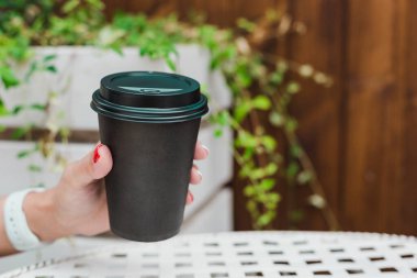 Sıfır israf kavramı - bir kızın elinde sade bir kahve fincanı bir kafedeki yaz masasının arka planına karşı. Fotokopi alanı olan bir yan görünüm. Yatay yönelim.
