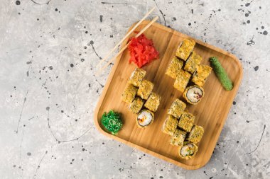 Japon restoranından büyük bir tabak dolusu fırında rulo ekmek, yemek çubukları, wasabi ve zencefil, açık gri arka planda, üst manzara. Yatay oryantasyon. Boşluğu kopyala.