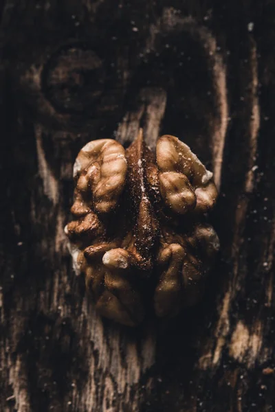 Walnut grain on a dark background close-up with a copy space. Vertical orientation.