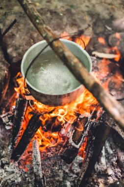 Tencere geceleri ormandaki çadırın yanında yanıyor. Vahşi doğadaki bir turist kampında çok güzel bir kamp ateşi. Ormanda hayatta kalmak. Ateşin üzerinde kazan var. Ağaçlardaki yangından çıkan duman. Ateşte pişirmek için fırın..