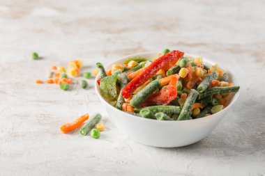 Donmuş sebzeler: hafif arka planda beyaz bir kasede sebze, çalı fasulyesi ve karnabahar karışımı. Fotokopi alanıyla yakın çekim. Yatay yönelim.